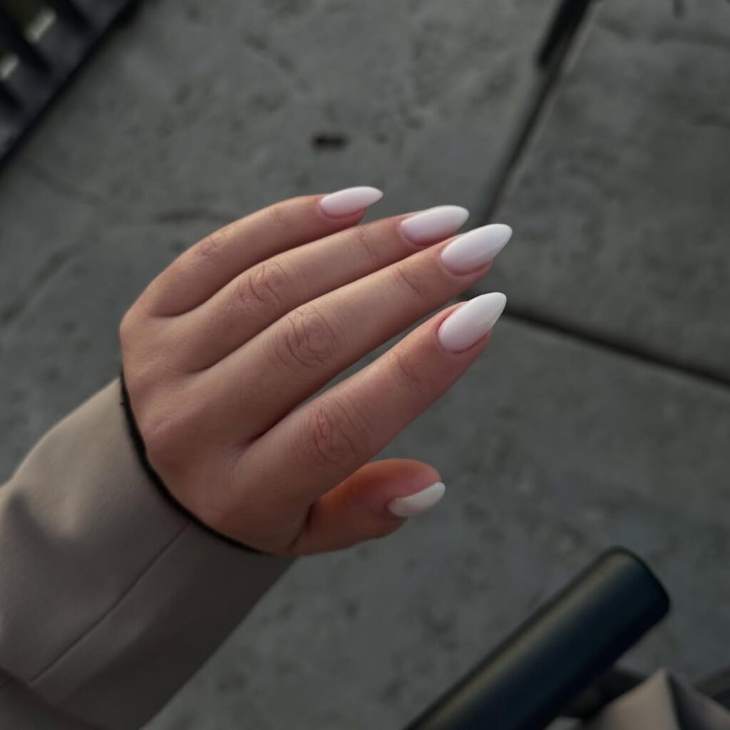 Mão de pele clara, com unha amendoada com esmalte branco gelo