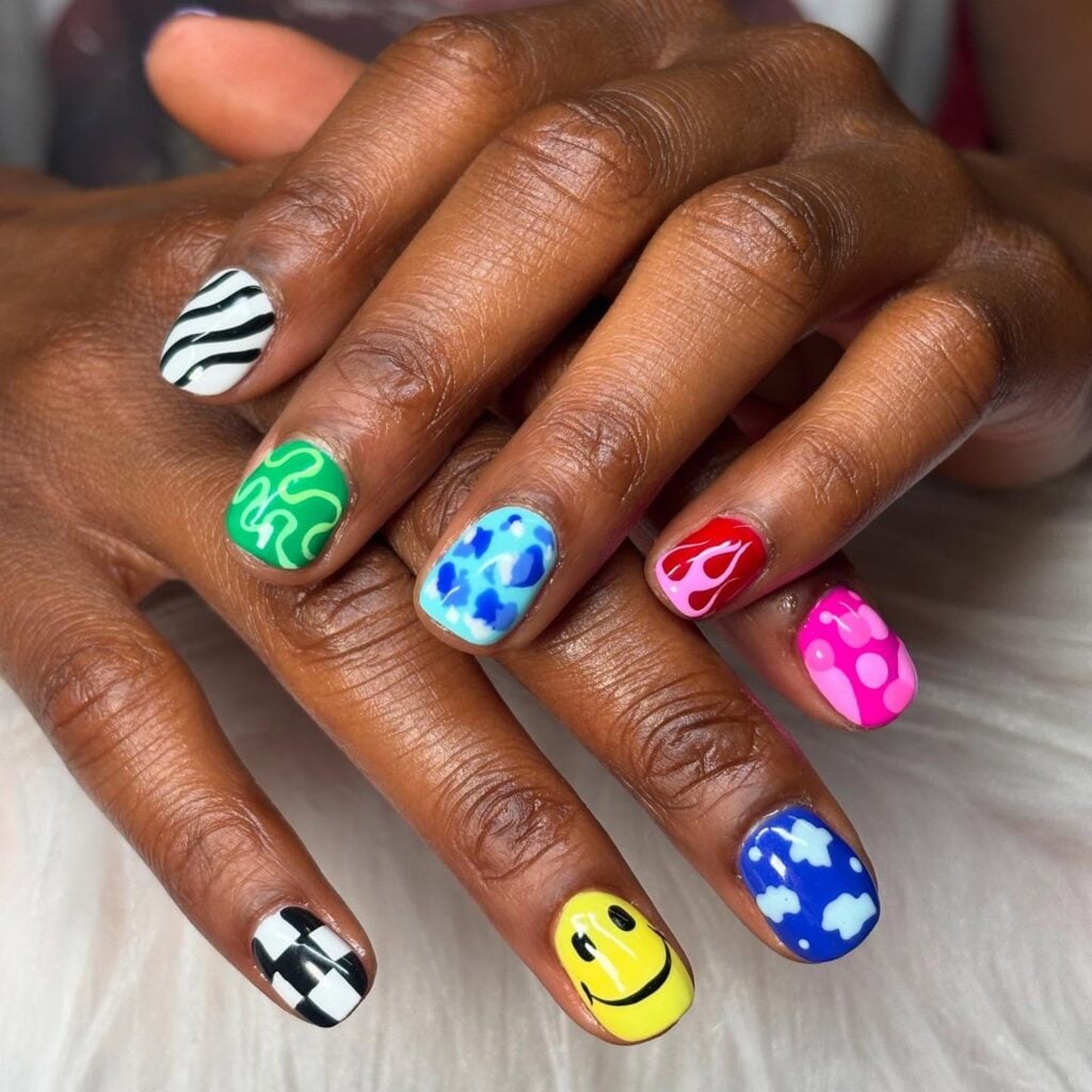 Mão de pele negra com unha azul, verde, vermelho, rosa, amarelo, preto e branco com unha maximalista checkerboard nails ou unhas de tabuleiro de xadrez com efeito quadriculado