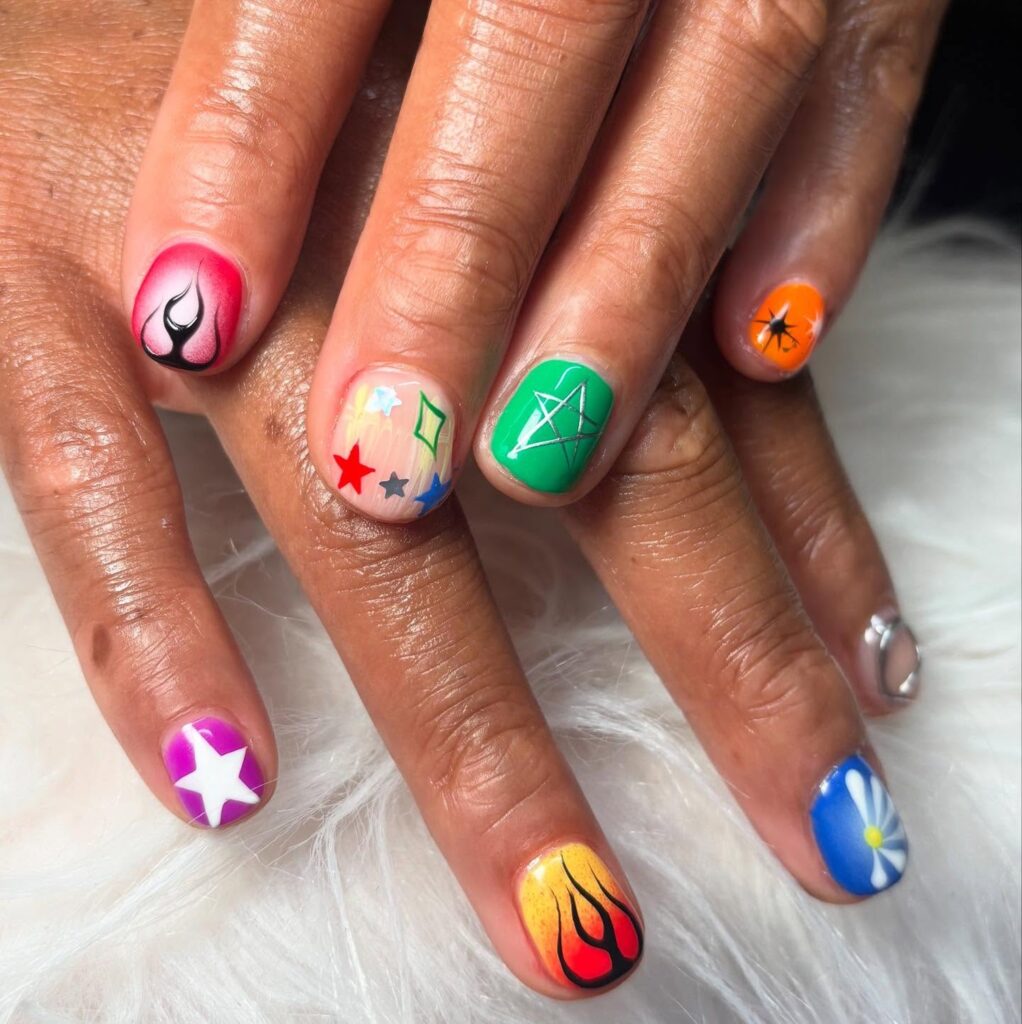 Mão de pele negra com nail art de estrela branca e rosa e unhas maximalistas