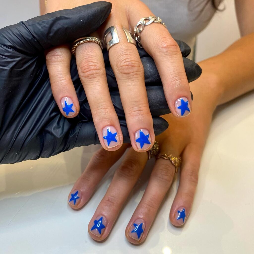 Mão de pele branca com nail art de estrela azul