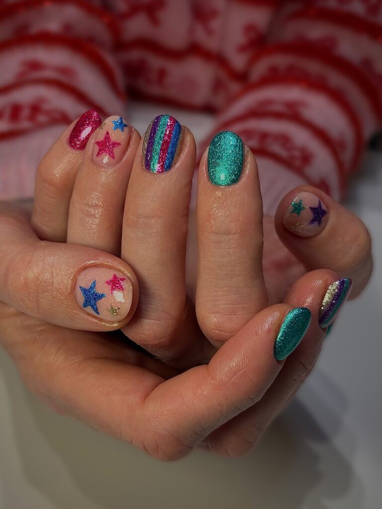 Mão de pele branca com nail art de estrela azul e rosa com glitter e brilho