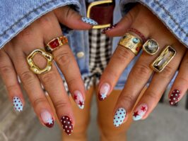 Unhas com poá em azul e marrom em mão de pele branca