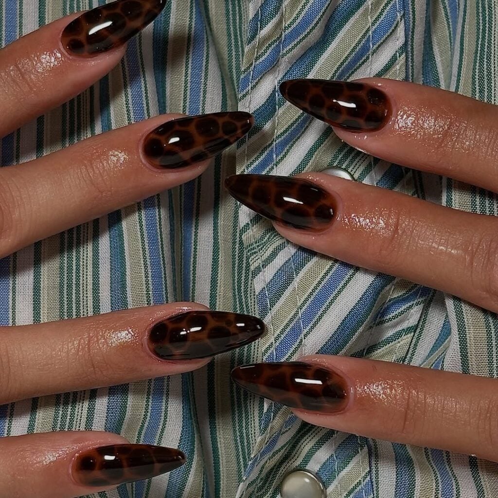 Mãos de pele clara, com unha stiletto com estampa de tartaruga