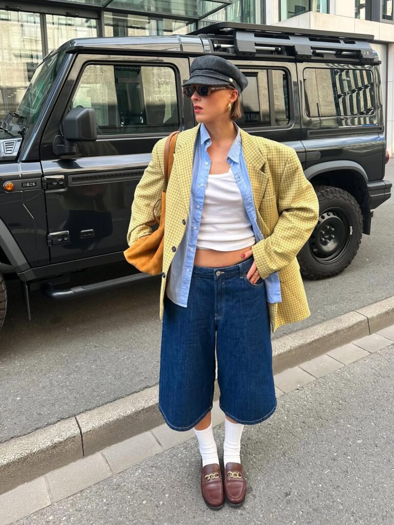 @lara_bsmnn com blazer, camisa social e cropped branco. Ela também usa jorts, mocassim marrom com meia e boina