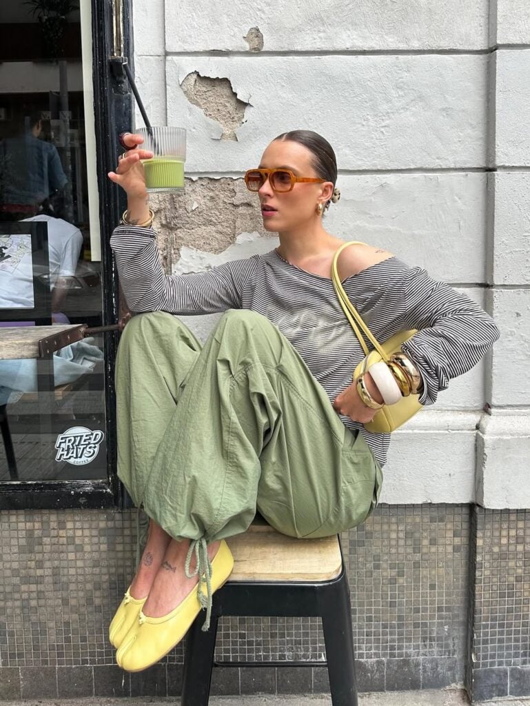 Mulher jovem, magra e de pele clara usando blusa, calça e sapatilha tabi