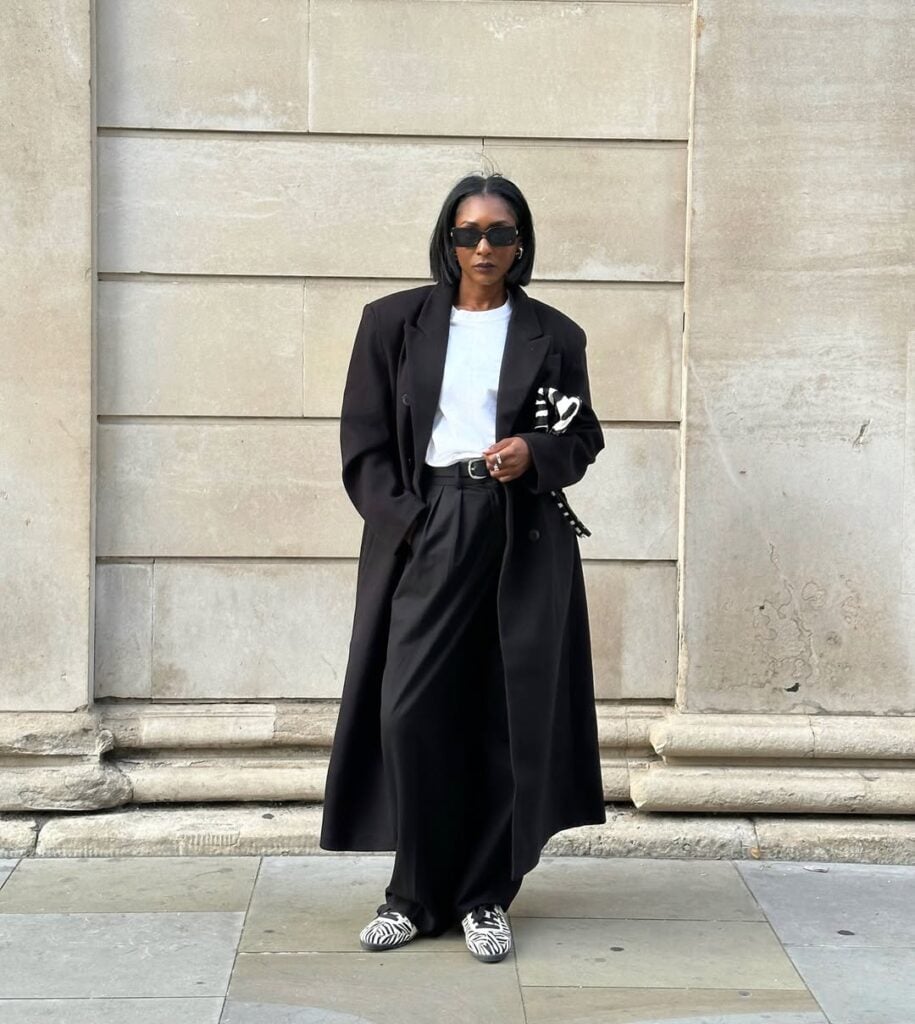 Mulher jovem, magra, de pele preta e com cabelos curtos. Ela usa look com tênis