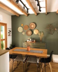 Sala de jantar com parede verde e cestarias e aparador em outro tom de verde