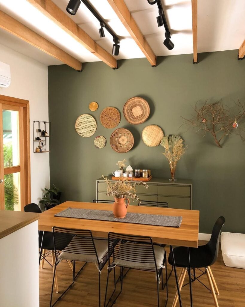 Sala de jantar com parede verde e cestarias e aparador em outro tom de verde