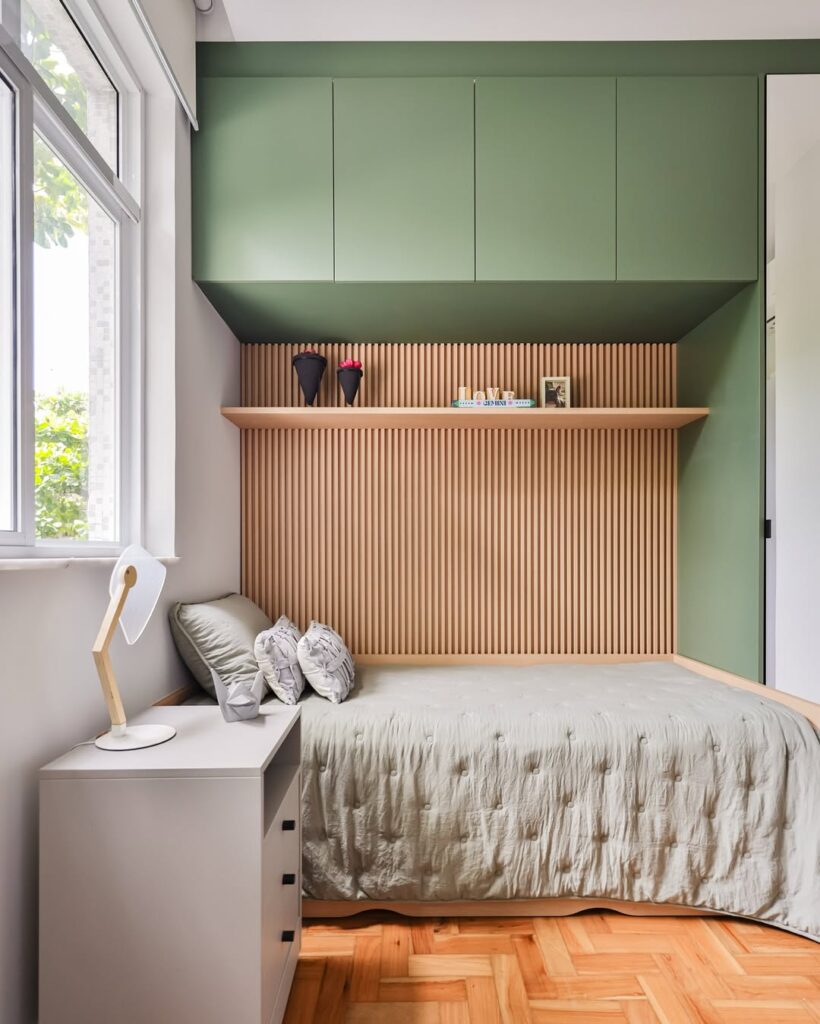 Quarto de solteiro com guarda-roupa verde e painel ripado em madeira clara