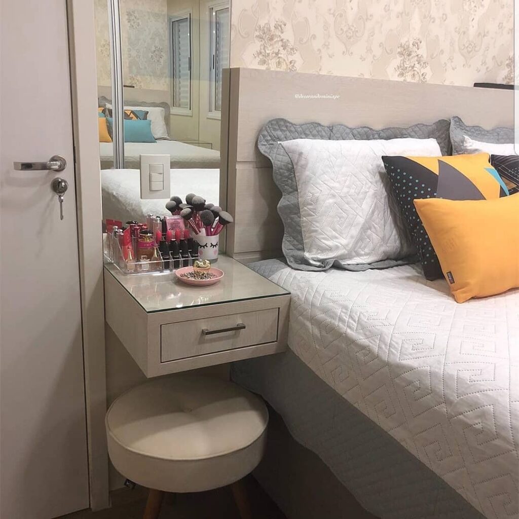 Quarto com mini penteadeira aérea ao lado da cama com espelho e banqueta