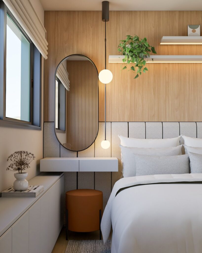 Cantinho da penteadeira no quarto ao lado da cama com espelho de borda preta e banqueta em tom de marrom