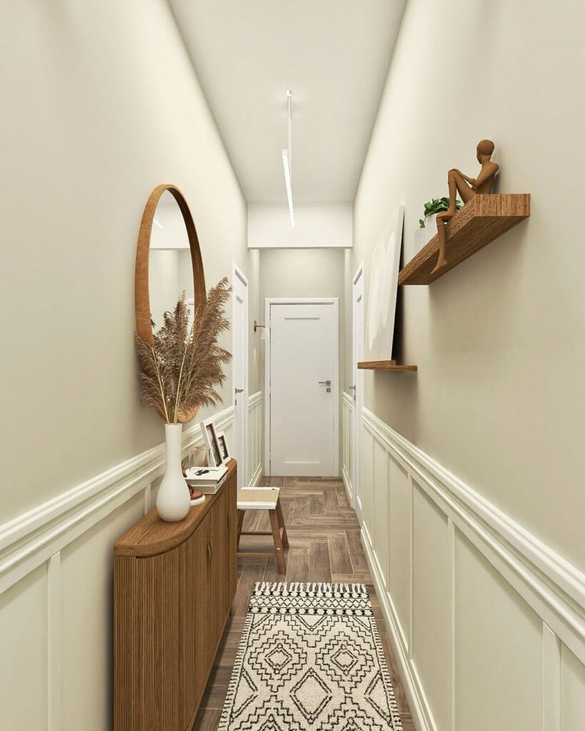 Corredor branco com aparador e prateleira de madeira, objetos decorativos e espelho redondo