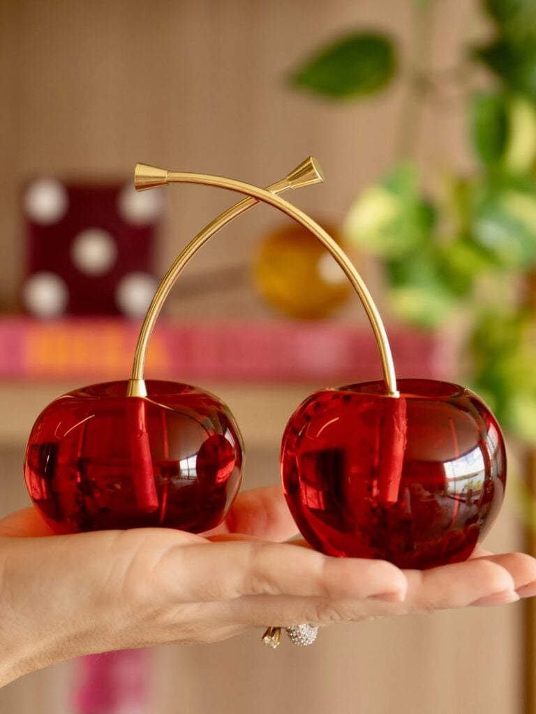 Objeto decorativo em formato de cerejas vermelhas com cabinhos dourados