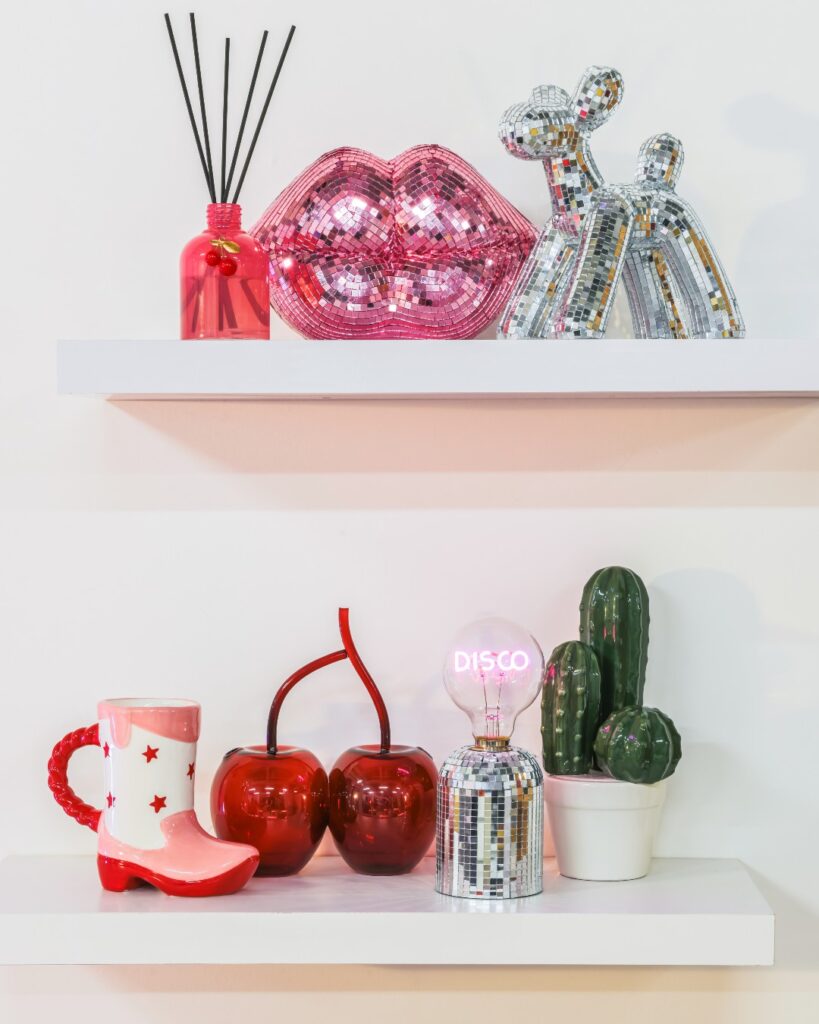 Prateleiras brancas com objetos decorativos como bota, cactus e cerejas