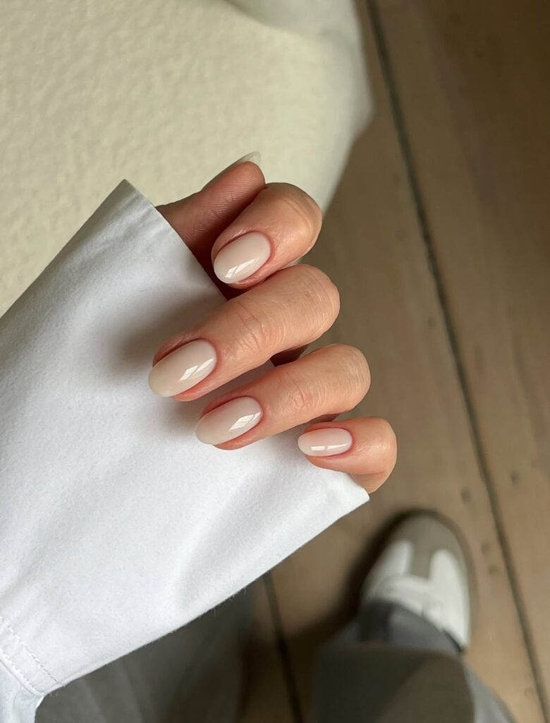 Mão de pele clara, com unha amendoada e unha off-white