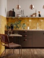 Cozinha sem armário superior, backsplash amarelo e louças aparecendo