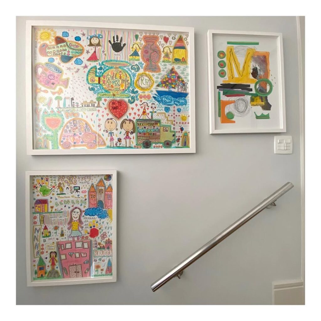 Parede com quadros de moldura branca com desenhos de crianças