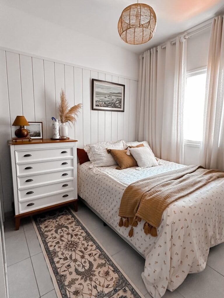 Quarto branco com detalhes em marrom, na almofada, manta e tampo da cômoda
