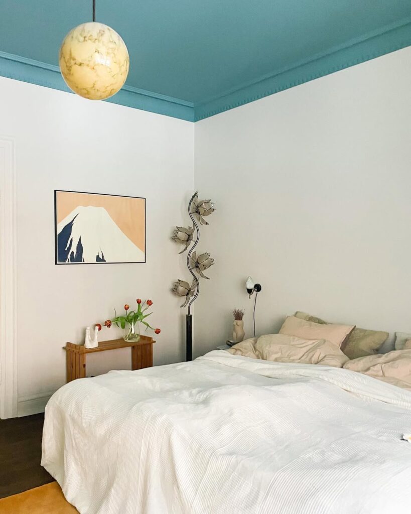 Quarto branco com poucos elementos e teto pintado de azul