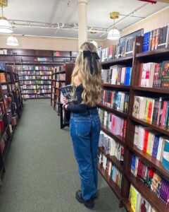 Mulher de pele clara, com cabelo loiro em uma biblioteca