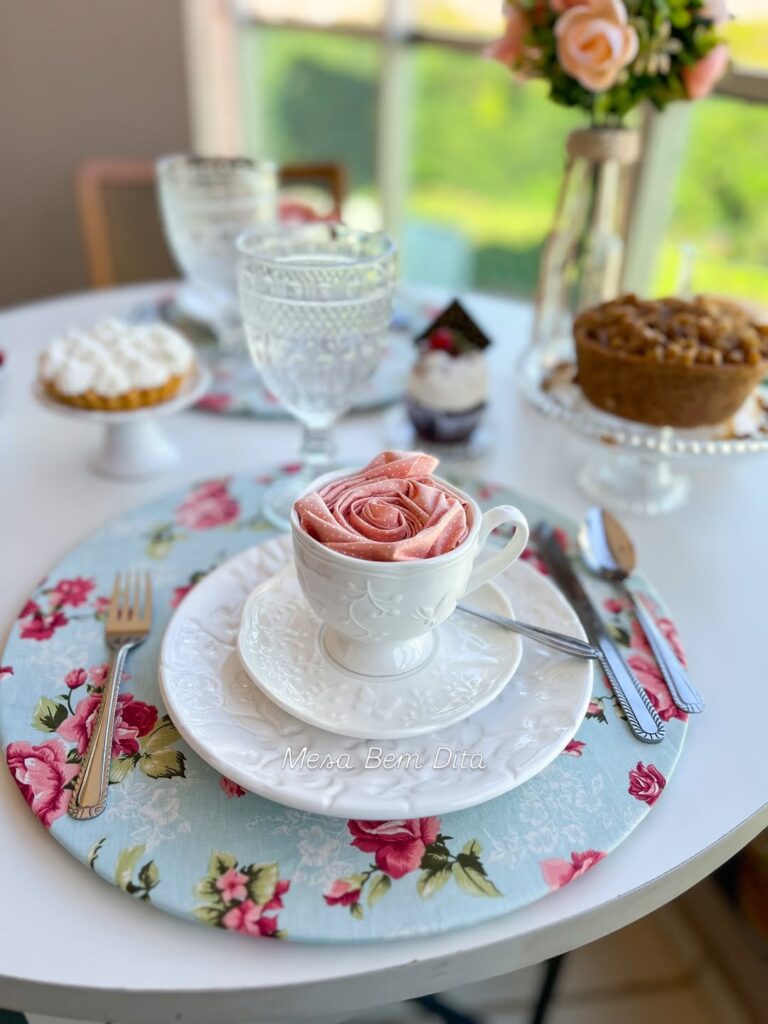 Mesa posta com louça branca e sousplat com rosas