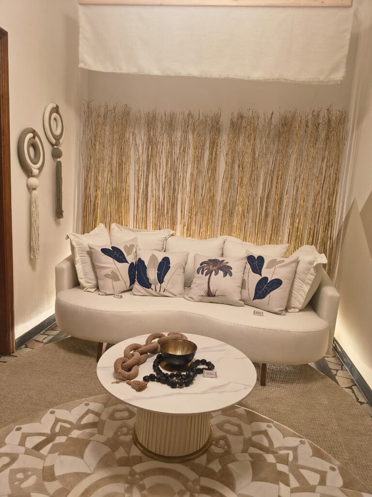 Ambiente com sofá claro curvo e pés de madeira, com almofadas claras e detalhes em azul