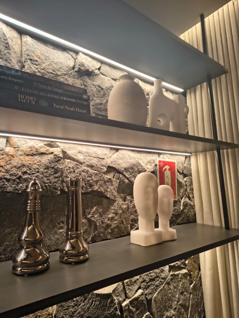 Parede de pedras, prateleira no estilo industrial com esculturas