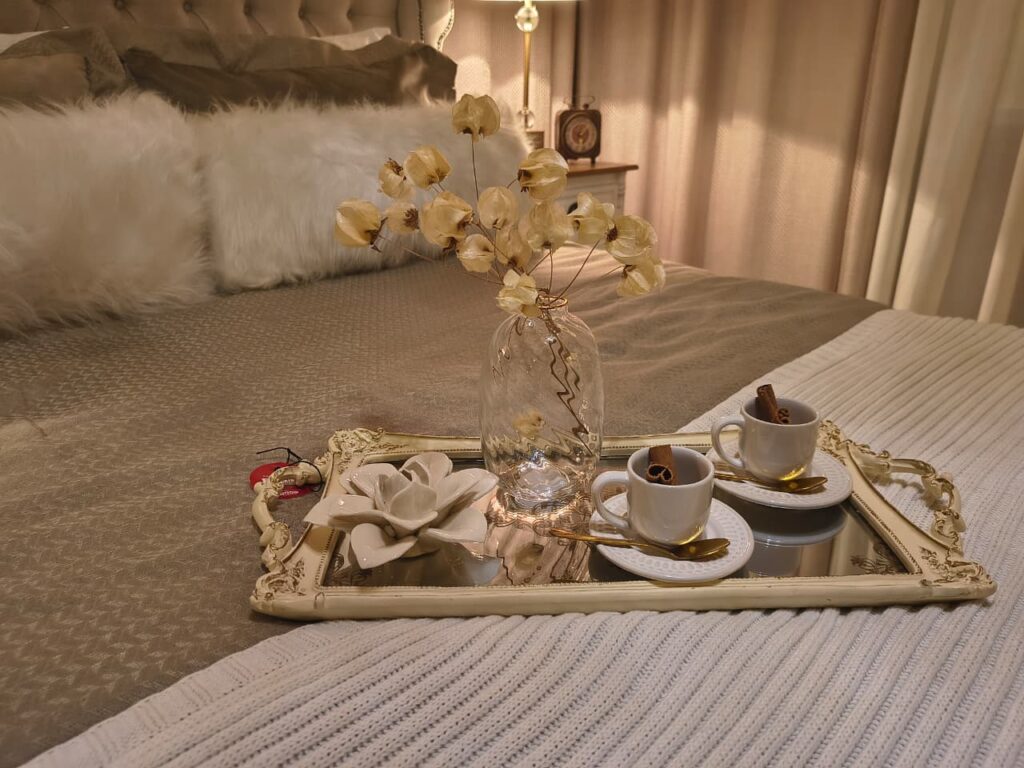 Bandeja decorativa com borda provençal e detalhes dourados, vaso com flores e xícaras brancas