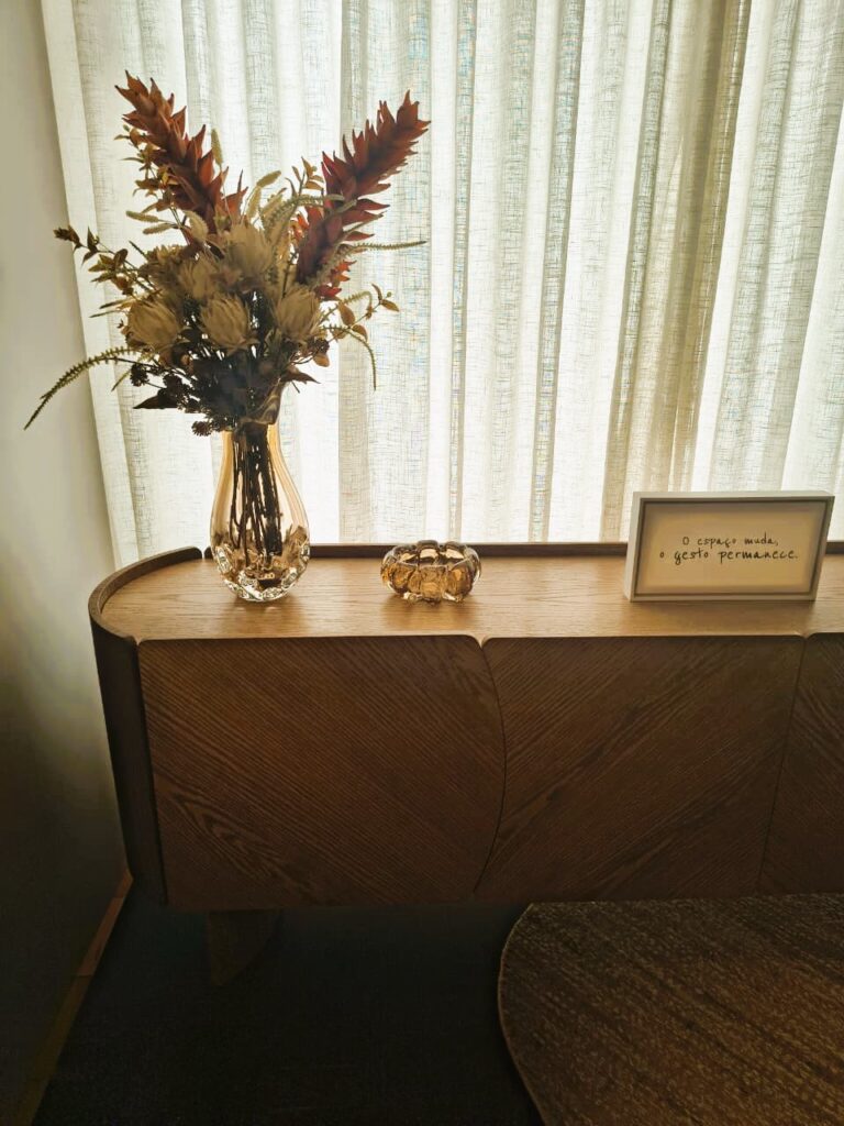 Buffet de madeira com vaso de vidro e flores secas