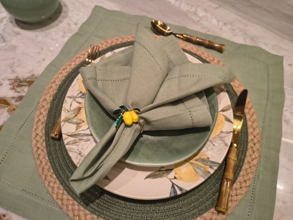 Mesa posta em tom de verde com prato e anel de guardanapo com limões-sicilianos