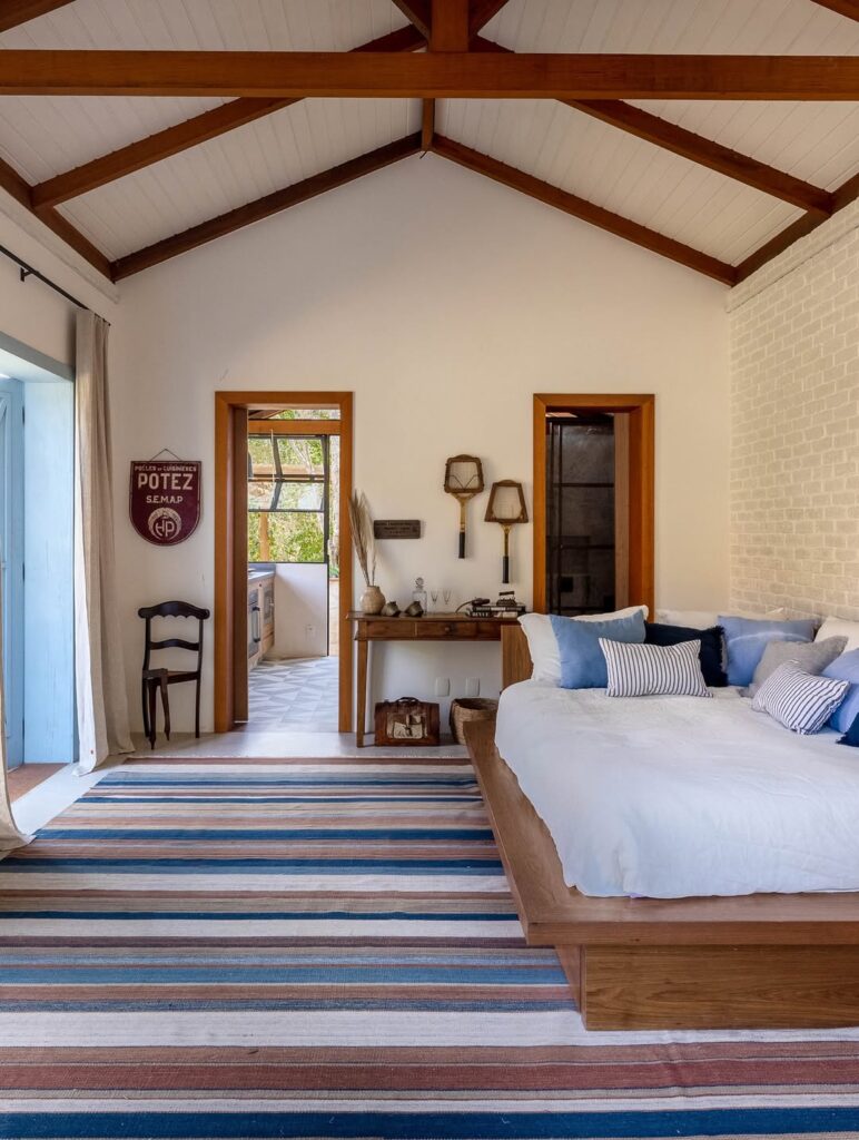Sala ampla com pé direito alto e tapete listrado em azul, marrom e bege