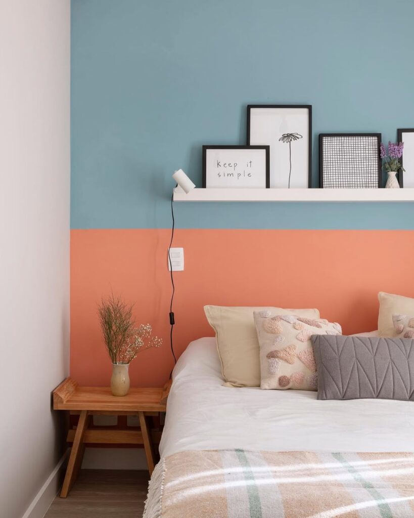 Quarto com prateleira acima e quadros e meia parede azul e meia parede rosa