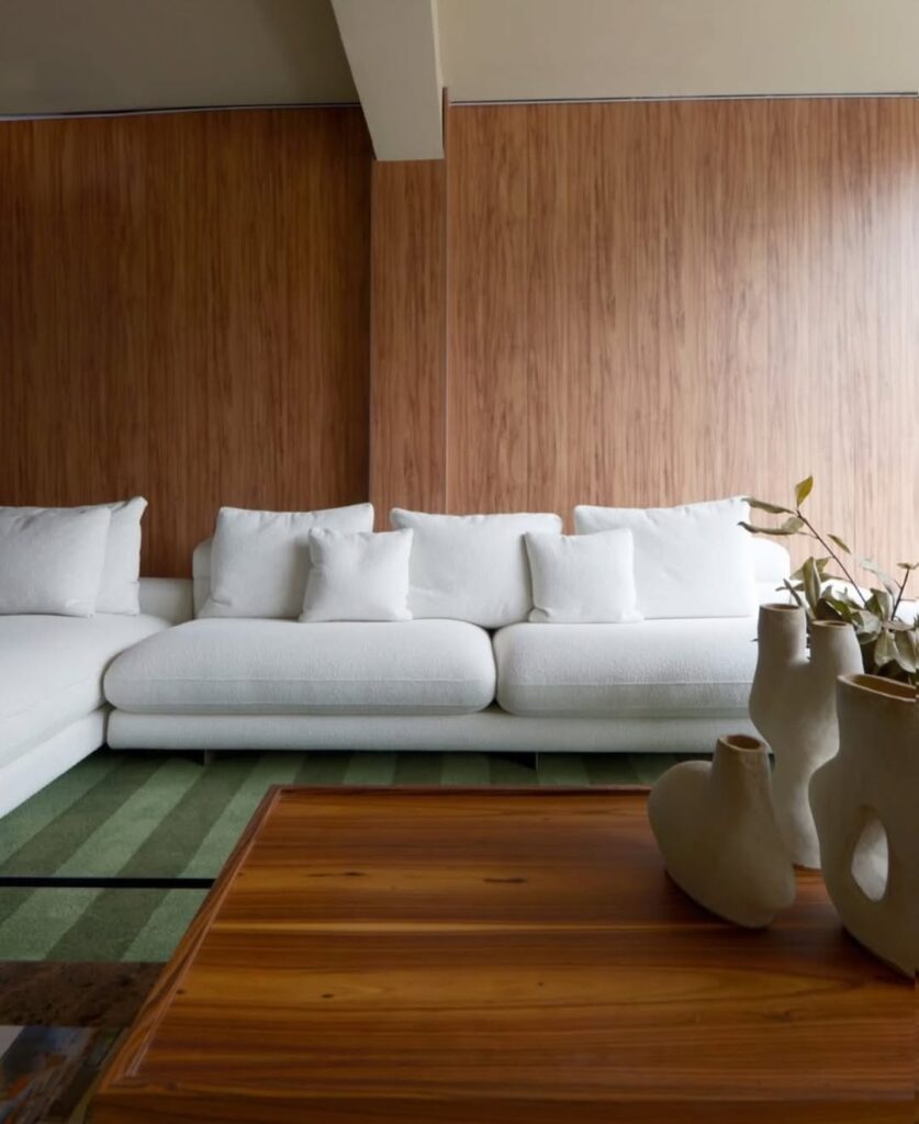 Sala com sofá confortável branco e tapete listrado em tons de verde