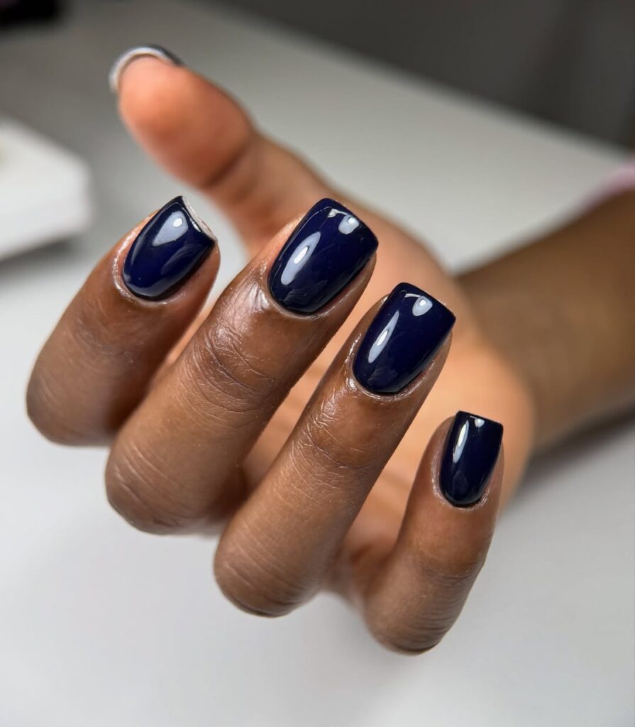 Mão de pele preta, com unha quadrada azul-marinho
