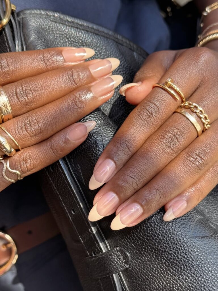 Mãos de pele preta, com anéis em dourado e unha amendoada bege