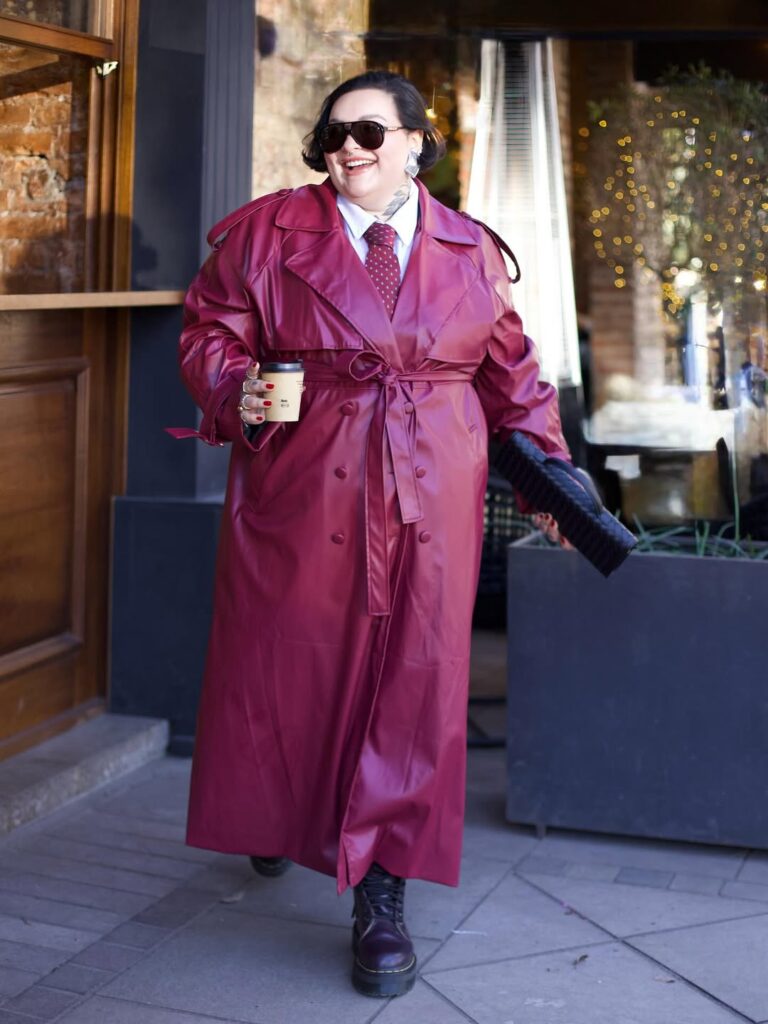Mulher jovem plus size com casaco vermelho longo, gravata vermelha e coturno