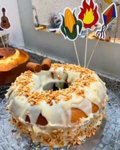Bolo decorado com brigadeiro branco, amendoim triturado, paçocas e desenhos de milho, fogueira e balão de São João