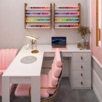 Mesa em L para salão de manicure, cadeira com assento rosa e prateleiras com esmaltes