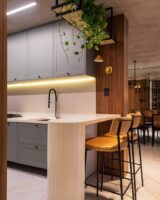 Cozinha com península branca e banquetas com assentos e encostos de couro e base de metal
