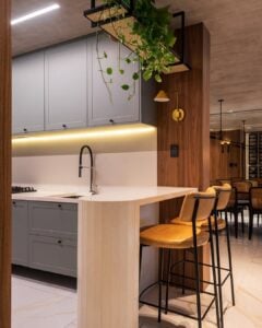 Cozinha com península branca e banquetas com assentos e encostos de couro e base de metal