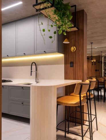 Cozinha com península branca e banquetas com assentos e encostos de couro e base de metal