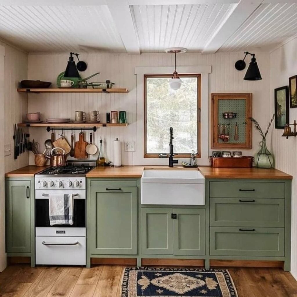 Cozinha no estilo farmhouse com armário verde, pia branca e bancada de madeira