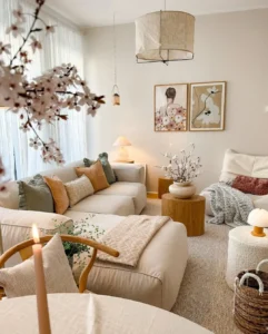 Sala de estar com paredes e sofás claros com mantas e almofadas, mesa de centro redonda e quadros na parede