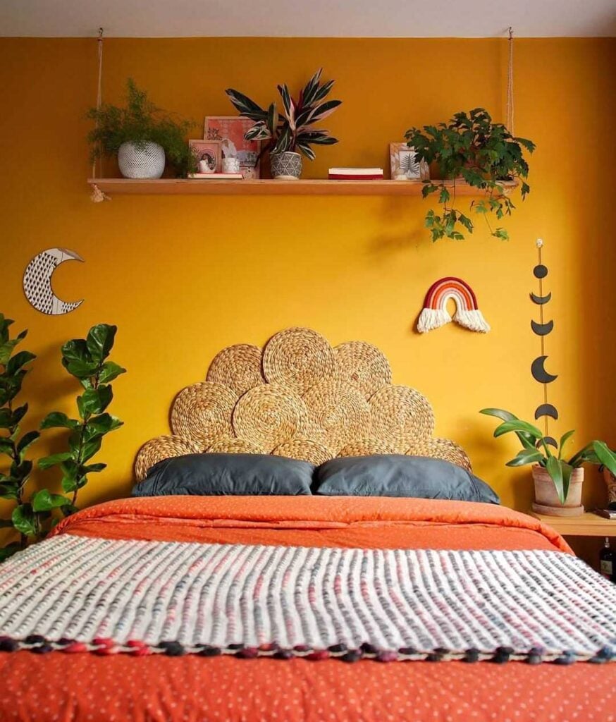 Quarto com parede amarela e cabeceira feita com sousplats de palha