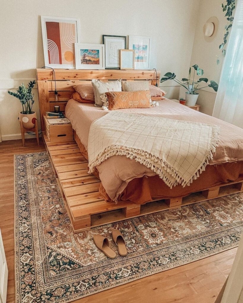 Quarto com cama feita de pallet na cor natural e quadros na cabeceira