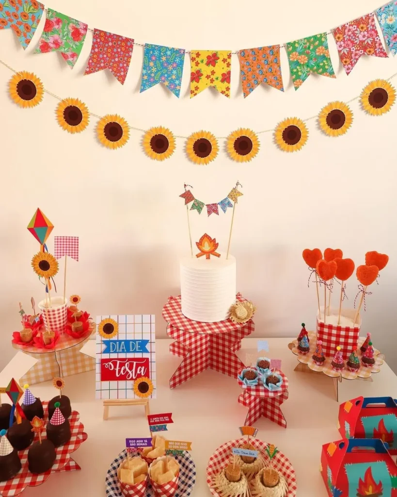 Mesa de São João com itens xadrez, fogueiras e balão de papel