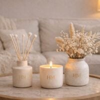 Vela, aromatizador de ambiente e vaso com florzinhas
