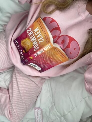 Mulher de pele clara, com conjunto rosa e livro