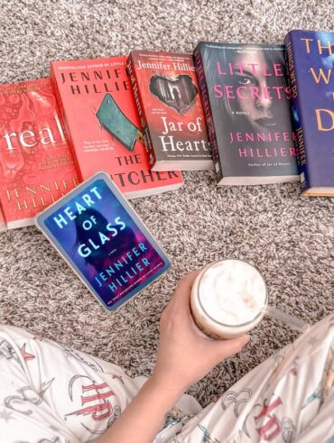 Pessoa sentada no chão, segurando um café gelado e livros na sua frente