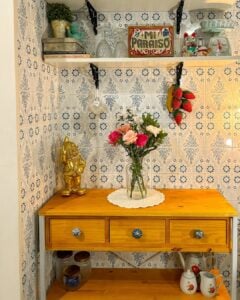 Cantinho com balcão de madeira, guardanapo de crochê e vaso de flores, azulejos com flores azuis e enfeites